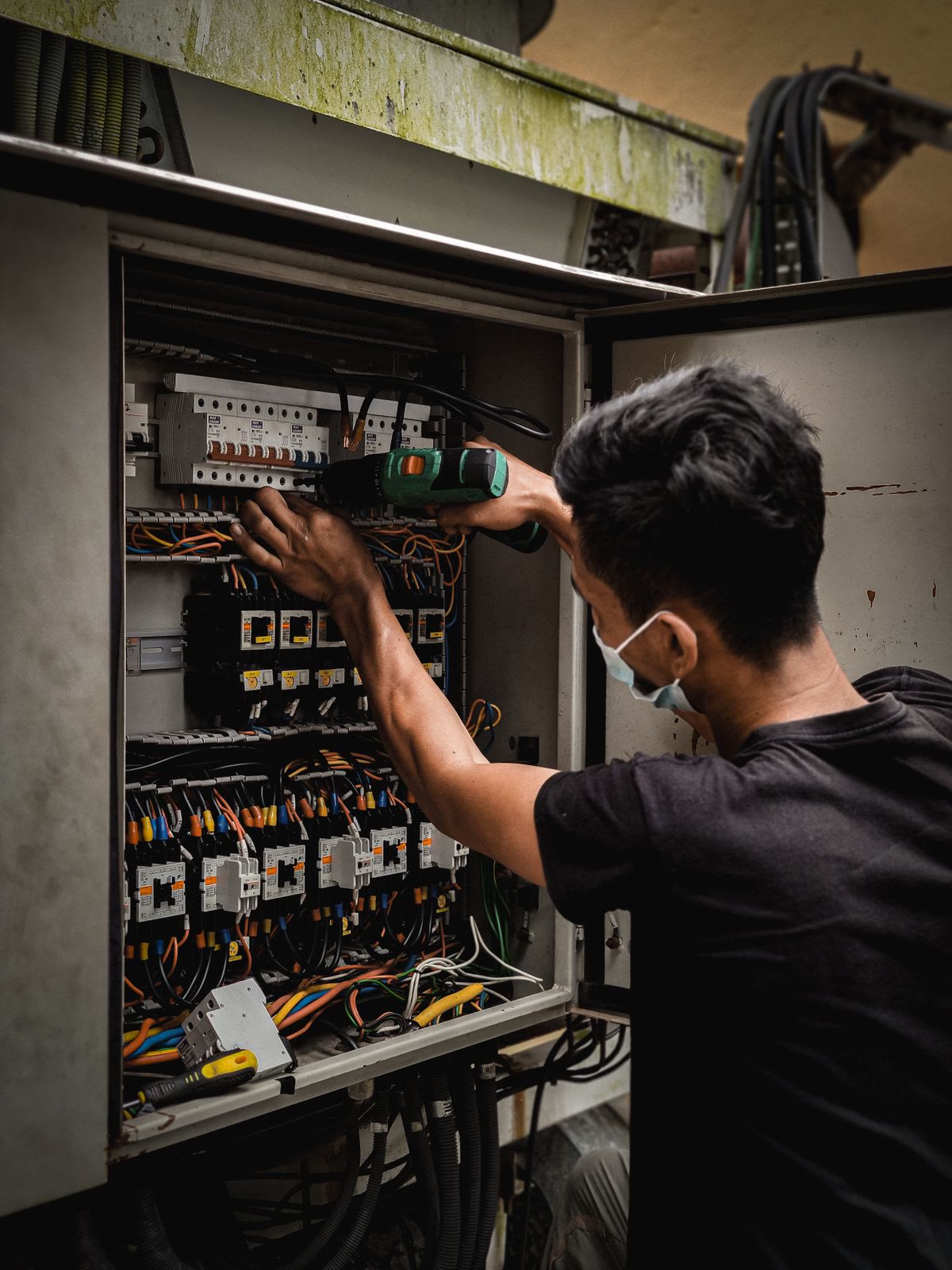 An electrician wiring an open breaker panel