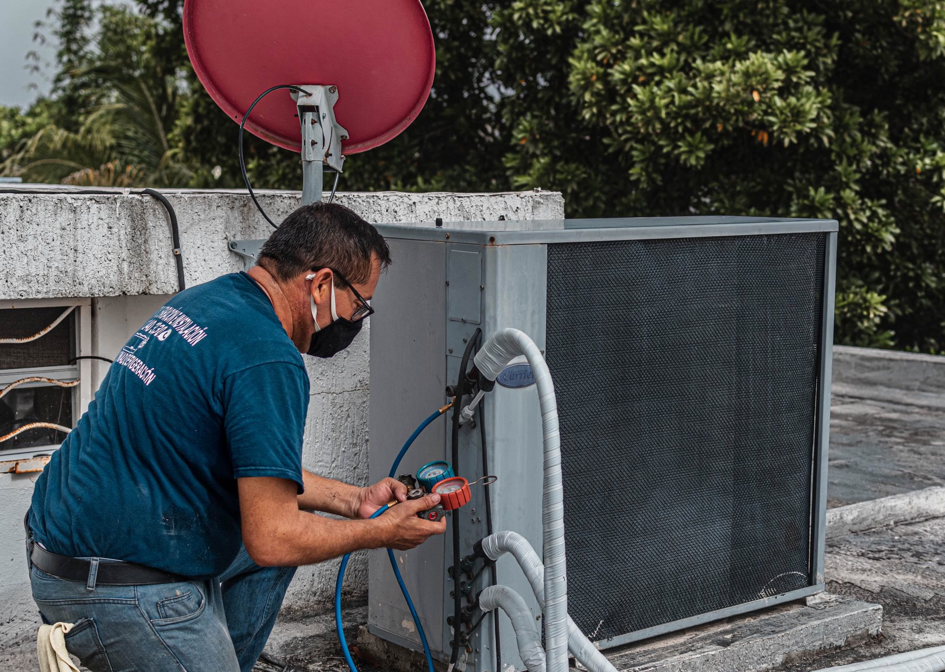 A technician checking an air conditioner with gauges, in daylight