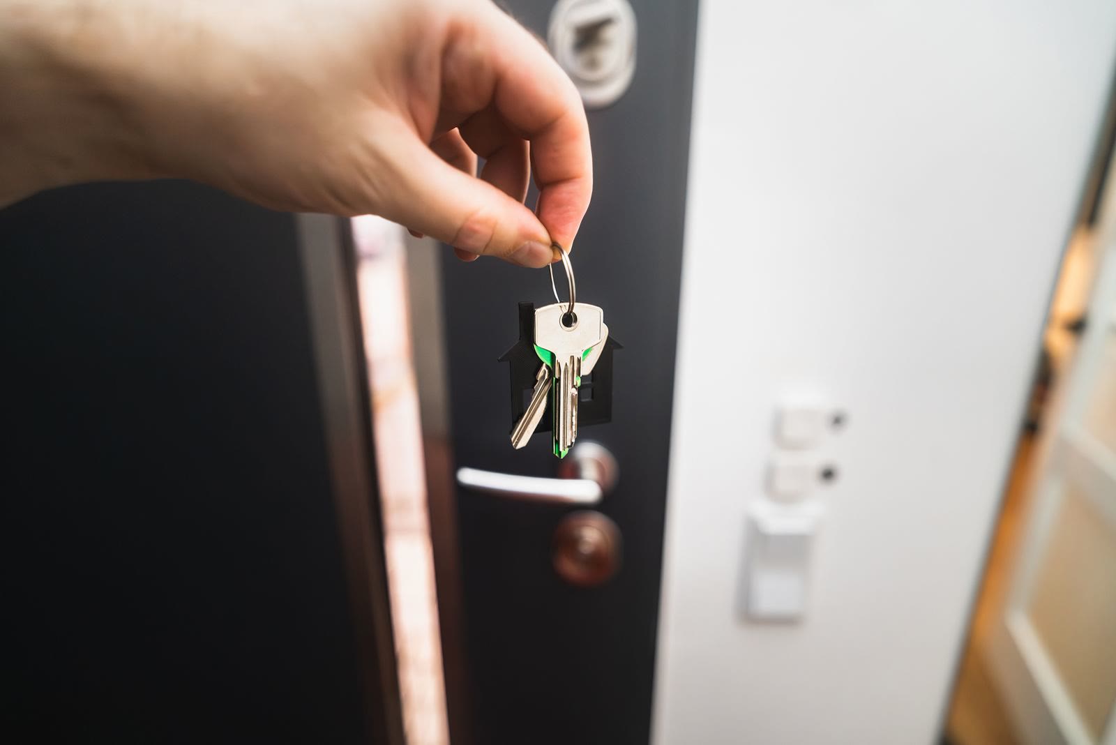 A hand holding house keys in front of a front door